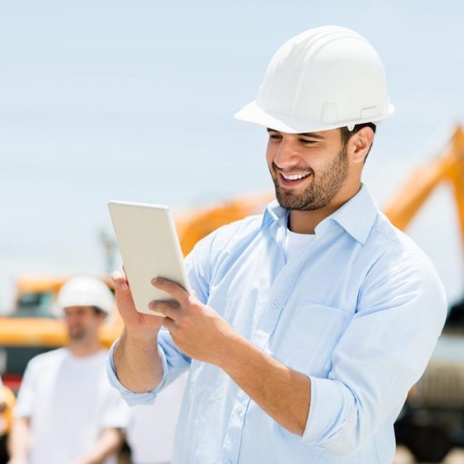 An estimator confidently using Zedops software on a laptop, with construction blueprints in the background.